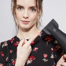 brunette with wet hair pointing at hairdryer