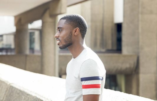 360 waves: Man with short afro hair in 360 waves with facial hair wearing a grey t-shirt, standing outside