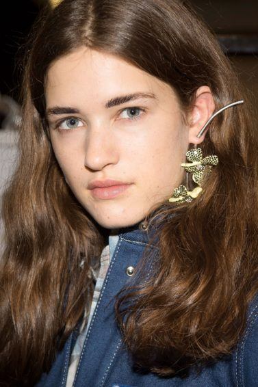 Hair thickening shampoo: Close-up of a brunette model with thick medium length hair tucked behind her ears, backstage at acne FW18 runway show