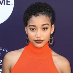 close up shot of amandla stenberg with baby afro hairstyle, wearing orange top on the red carpet