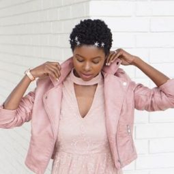 close up shot of woman with fluffed out short natural hair, wearing stars in her hair and all pink outfit, posing outside