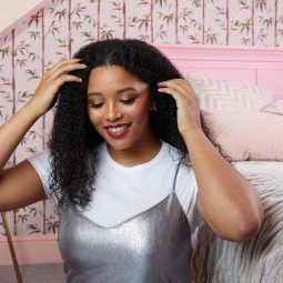 Woman with long curly hair in her bedroom