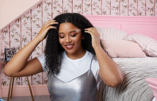 Woman with long curly hair in her bedroom