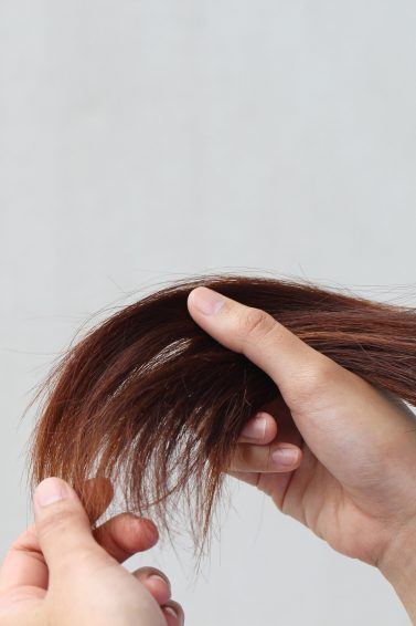 Woman holding her damaged, split hair