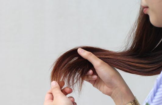 Woman holding her damaged, split hair