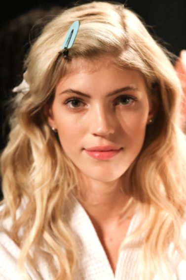 blonde model backstage with wavy hair with hair clips in her fringe