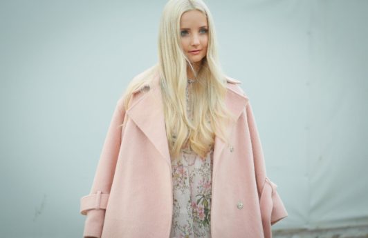 Purple shampoo: Blogger at fashion week with long light blonde blow-dried hair wearing a baby pink overcoat