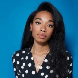 Blow out natural hair: Close-up of a woman with straightened dark brown natural hair with a sweeping side fringe, wearing a black and white polka dot shirt.