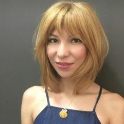 woman with a line with bangs hairstyle wearing blue denim dress and pearl necklace