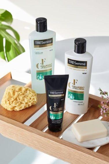 Photo of a bath shelf, with the TRESemmé Collagen+ Fullness range on it, along with a loofa and a bar of soap.