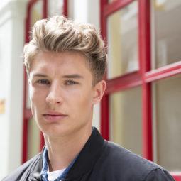 easy hairstyles for guys: man with blonde curly hair swept up into a quiff