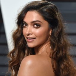 Bollywood hair: Deepika Padukone with long curly brown to caramel brown hair, wearing a black dress on the red carpet