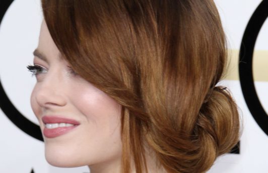 side view of emma stone with a side sweeping undone bun updo at golden globes