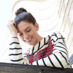 hair updos: brunette model with hair styled in a high fishtail braided bun wearing stripe tshirt