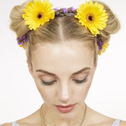 close up shot of blonde model with flowers in her space buns