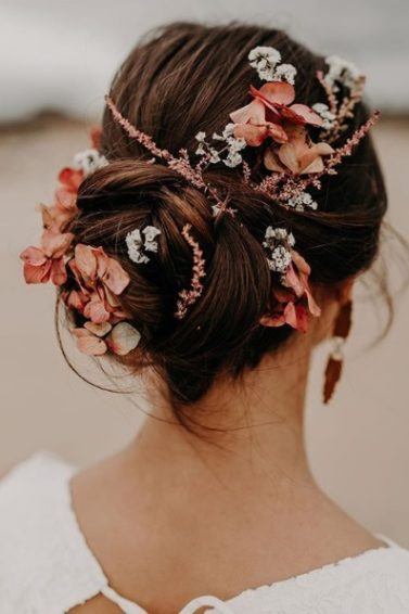 Wedding updos: Back view of a brunette woman with her hair in a twisted updo with pink, peach and white flowers in