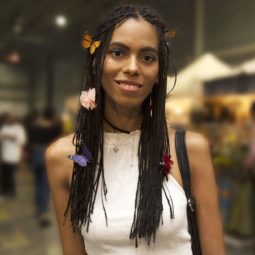 Model with long box braids with colourful butterflies places in hair from Afropunk