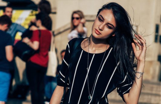 bruentte street styler with glossy hair swept to one side wearing an all in one stripe jumpsuit