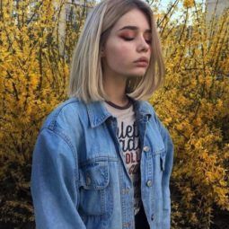 photo of a woman in a field wearing a denim jacket with a grungey 90s bob hairstyle