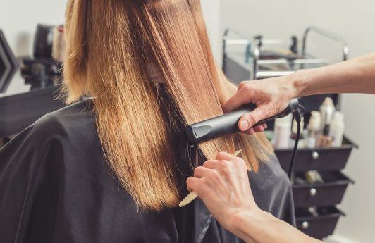 Woman getting hair hair straightened in a salon