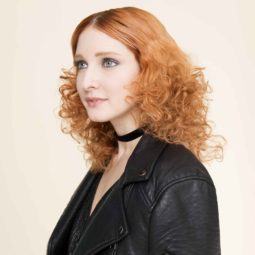 a look of a curly red hair woman wearing black leather jacket