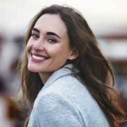 Woman smiling in the street with medium brown thick hair with slight curl