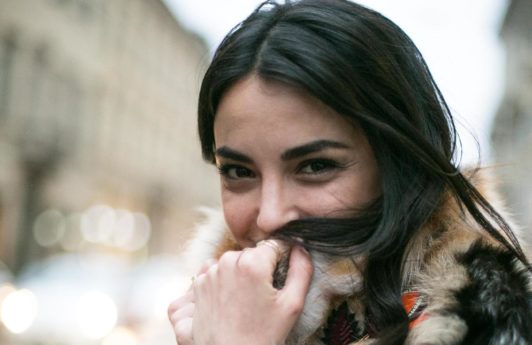 Hot oil treatment: Woman with long dark brown tousled hair, wearing big fluffy jacket outside