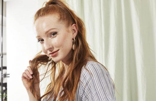 Woman touching her long red hair smiling