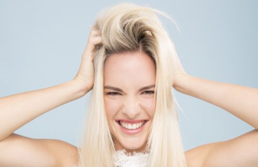 blonde model running hands through roots of hair looking in distress