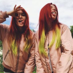 Bella with twin sister Dani Thorne posing wearing pink jackets and long straight hair dyed in a red to yellow ombre