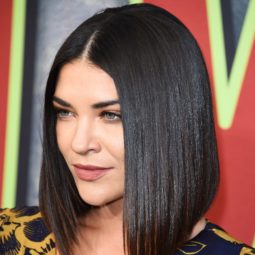 Angled bob: Close-up of Jessica Szohr with a dark brunette sharp angled bob, wearing a blue and yellow print dress