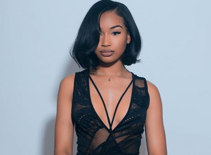 close up shot of woman with short sleek weave hairstyle with side swept fringe, wearing all black and posing