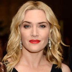 kate winslet in a black v neck dress with shoulder length blonde wavy hair