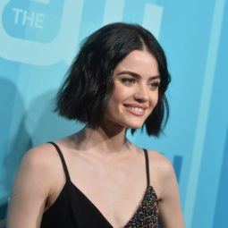 lucy hale with with wavy black hair on the red carpet smiling