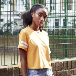 hairstyles for black women: close up shot of a woman with a dark brown afro hair fashioned into a braided, low ponytail posing outside