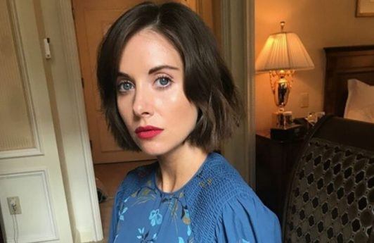 close up shot of alison brie with short hairstyle with blue denim dress, wearing red lipstick