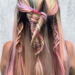 Back view of a woman with long, straight, multicoloured pastel hair in multiple half-up DNA braids.