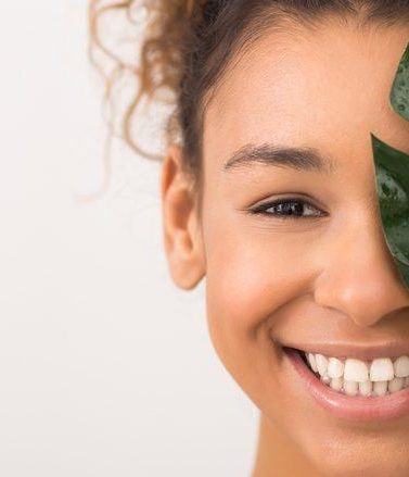 Woman with brunette curly hair holding a leaf