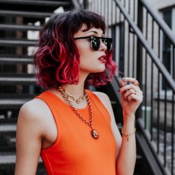 Woman with a black and red ombre wavy bob with a fringe