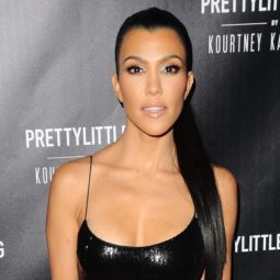 Kourtney Kardashian dark long hair in high ponytail over one shoulder