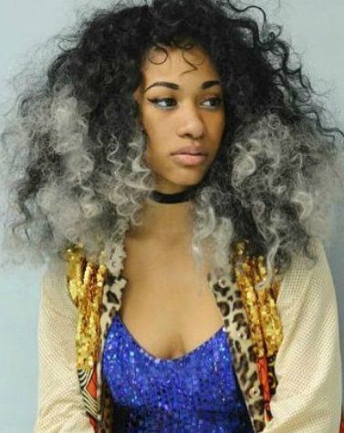 close up shot of woman with grey ombre natural hair, wearing blue top and jacket and necklace