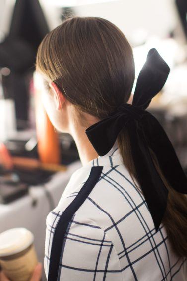 backstage shot at Tory Burch, of model with ribbon in her hair, getting her makeup done