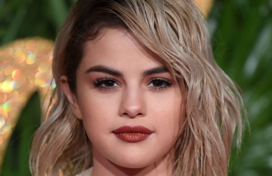 front view of selena gomez with blonde shoulder length hair and dark roots