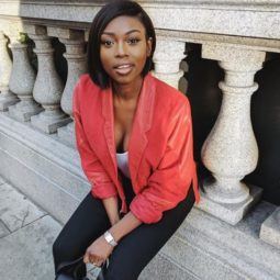 close up shot of patricia bright with short bob hairstyle styled to the side, wearing red jacket and black jeans