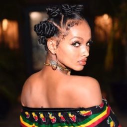 bantu knots of weave: shot of woman with sleek bantu knot hairstyle standing outside wearing a bardot top