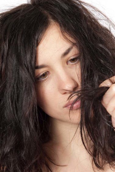 model looking at her brown frizzy hair