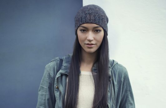 Woman with long straight dark brown hair wearing a knitted beanie