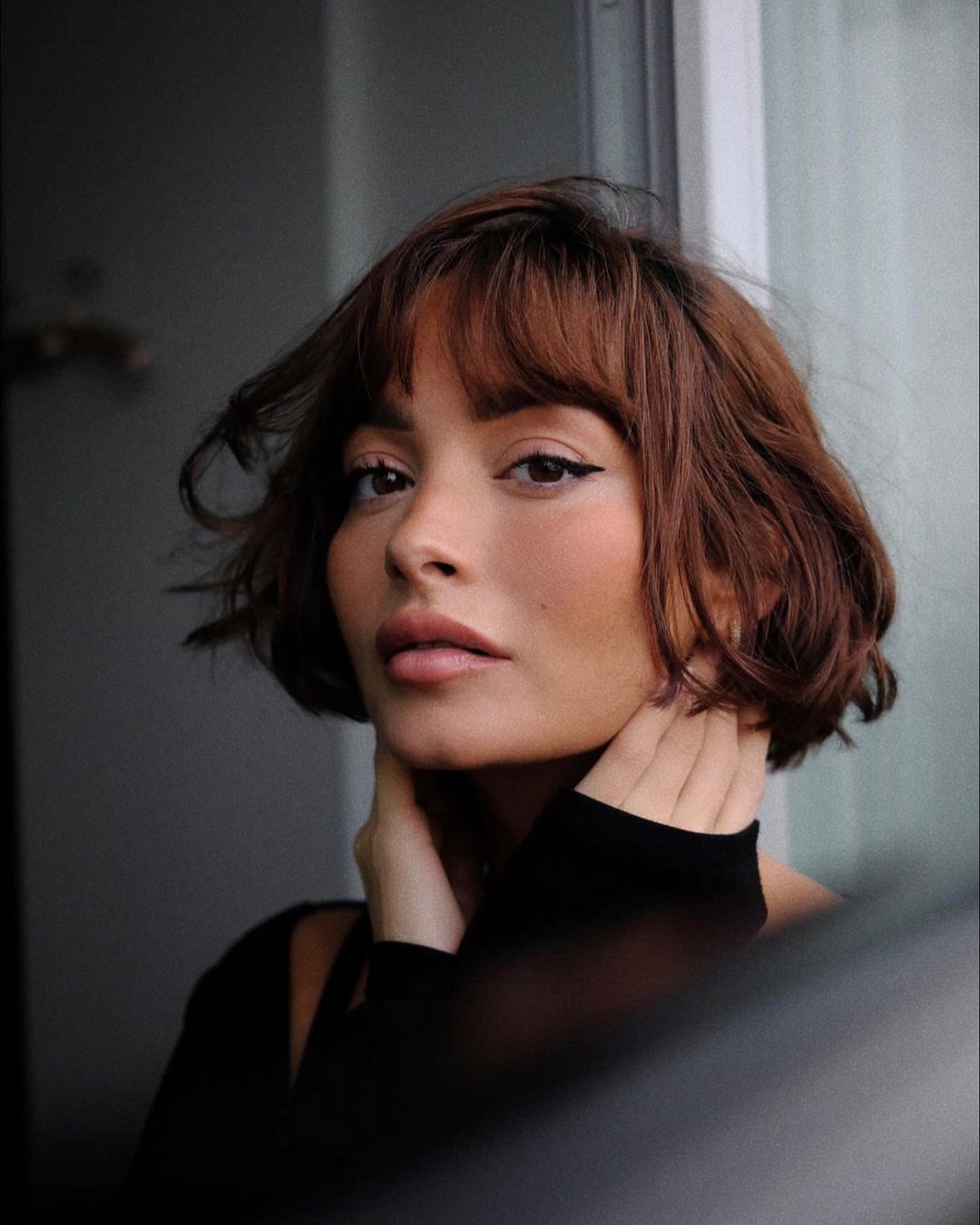 Model Taylor La Shae with a red French bob wearing a black jumper.