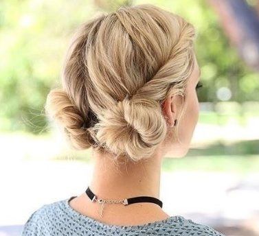 landscape shot of a blonde woman wearing a blue patterened top with her hair in twisted low macaron buns