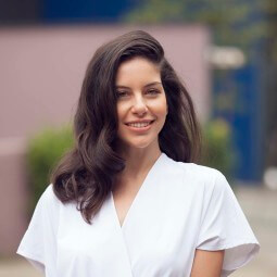 lifestyle shot of a brunette model with shoulder length vintage curls with a side parting wearing a white v neck top